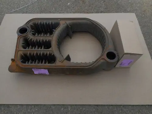 Remeha-Zwischenglied aus Metall mit mehreren gerippten Kammern, rostbraunem Finish, auf einem Karton platziert.